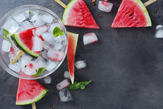 Watermelon Slices On Sticks With Ice Cubes On Table