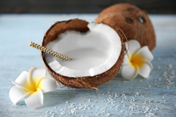 Tasty milk shake in coconut with flowers on table