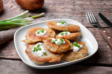 Plate with tasty potato pancakes for Hanukkah on wooden table