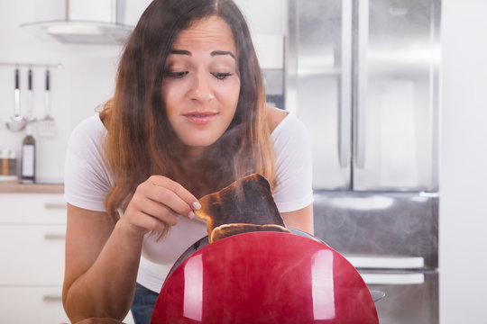 Woman Taking Burnt Toast Out Of The Toaster
