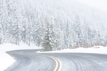 Beautiful winter scene with icy slick road driving situation curving road covered with snow and snowy trees all around