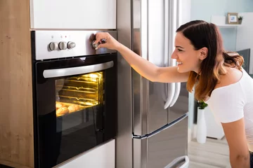 Foto op Plexiglas Woman Using Microwave Oven In Kitchen © Andrey Popov