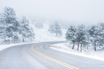 Beautiful winter scene with icy slick road driving situation curving road covered with snow and snowy trees all around