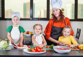 Three cute kids with mom making fruit salad