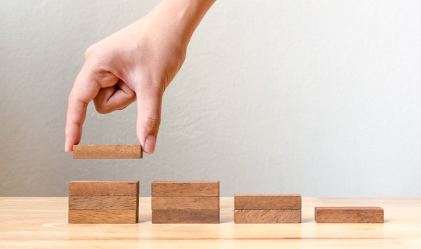 Hand arranging wood block stacking as step stair. Business concept for growth success process