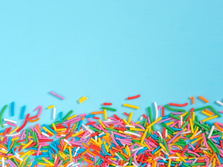 Obraz na płótnie Canvas Border frame of colorful sprinkles on blue background