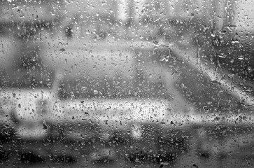 Rain drops on window with blur effect in black and white.