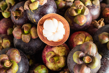 Mangosteen and cross section showing the thick purple skin and w