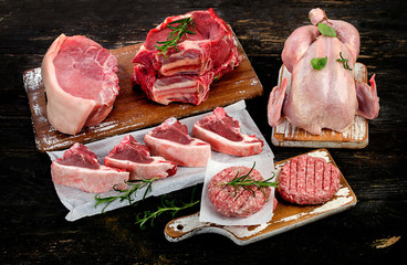 Different types of raw meat with herbs on  a wooden background.