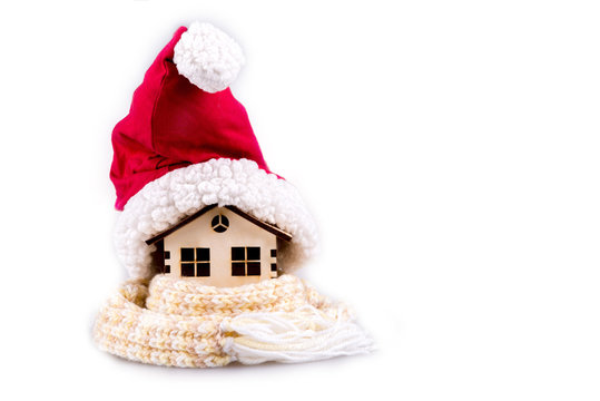 House wooden wrapped in a scarf, cap of Santa Claus, isolated on white.