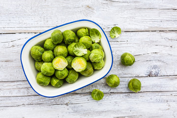 Fresh and raw brussels sprouts in a bowl on a wooden background. 