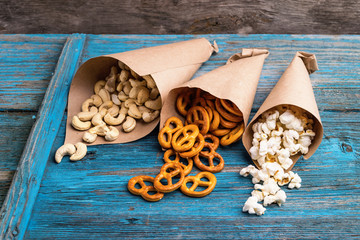 A variety of crunchy snacks ,nuts, crackers, popcorn , paper bag