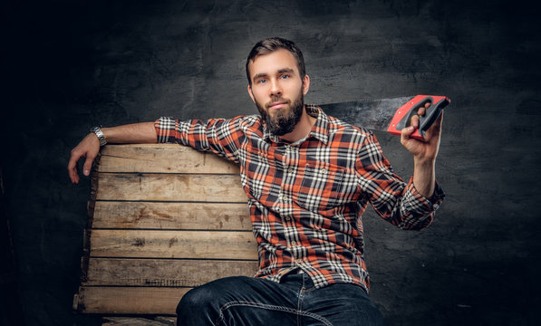 Bearded carpenter male holds handsaw.