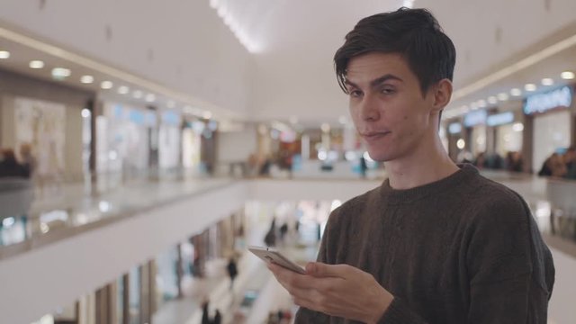 Young men using smartphone at shopping mall. Portrait