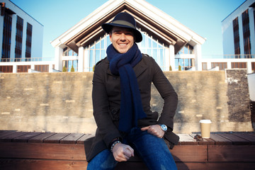 Trendy handsome young man in autumn fashion standing in urban environment.