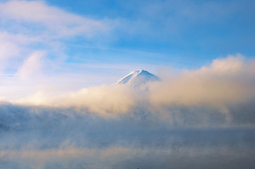 The peak of Fuji mountain with mist above Kawaguchiko lake background