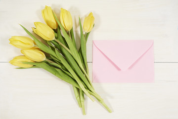 Bouquet of fresh tulips and envelope beside