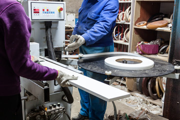 Workers using edge machine to make furniture at carpenters works