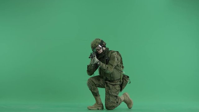 Soldier sitting and targeting at green screen