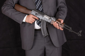 a man in a suit with a Kalashnikov assault rifle, a CIA agent, bodyguard