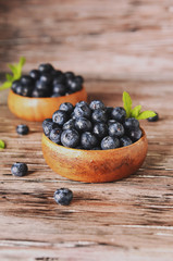 fresh bilberries or blueberries in small wooden bowls, selective focus