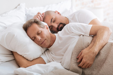 Obraz na płótnie Canvas Positive delighted non-traditional couple sleeping together