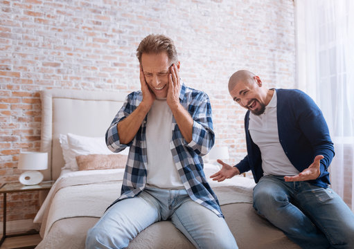 Choleric man screaming loudly on another person at home