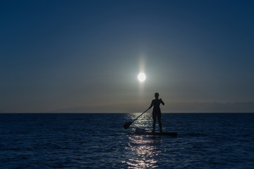 woman silhouette on paddle board night