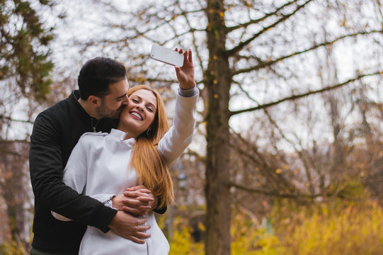Young attractive couple taking photo of themselves with smart phone, making a selfie