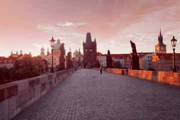 Prague, Czech Republic. Charles Bridge with its statuette at sunrise, Old Town Bridge Tower in the background.