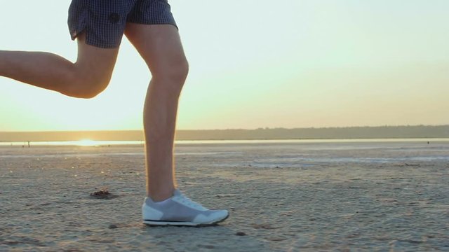 A young, short-haired, sports, white guy jogging on the bank of the river