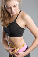 Hübsches sportliches Mädchen misst sich die Taille