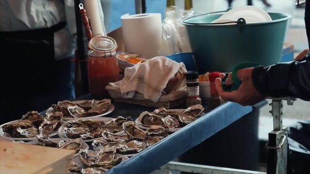 Salesman opening oysters at the seafood market. Real time video