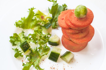 Pyramid from the sliced carrot with cucumber, Brussels sprouts and salad. White background. Vegetarian tower game. Fitness, healthy life food concept