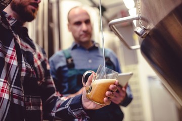 Owner pouring beer in glass at brewery