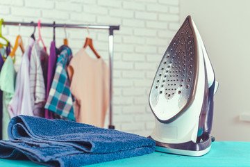 Iron on ironing board on light home interior background