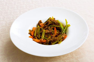 Meat fried with vegetables on the plate standing on the table