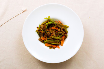 Meat fried with vegetables on the plate standing on the table