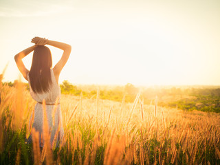 Beautiful girl in stylish summer dress walking in the field with flowers in sunlight,enjoying...
