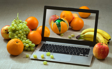 Christmas ball in the orange peel on the laptop screen