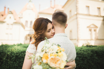 Beautiful fairytale newlywed couple hugging near old medieval castle