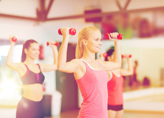 group of smiling women working out with dumbbells