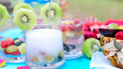 Champagne with fruit in a beautiful glass. Colorful Cakes on the occasion. Picnic table.
