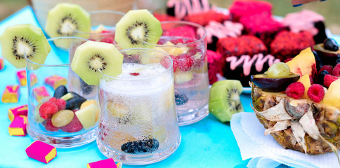Fototapeta na wymiar Champagne with fruit in a beautiful glass. Colorful Cakes on the occasion. Picnic table. 