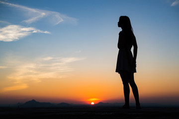 Fototapeta premium Silhouette of free woman enjoying freedom feeling happy at sunset. Serene relaxing woman in pure happiness