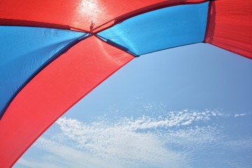 Blick aus einem rot - blauen Strand Zelt in den blauen Himmel