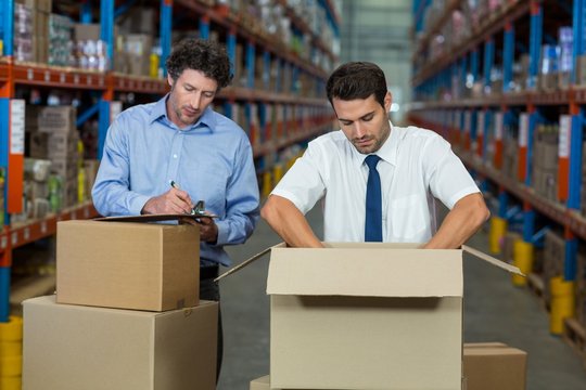 Two warehouse workers checking the boxes 
