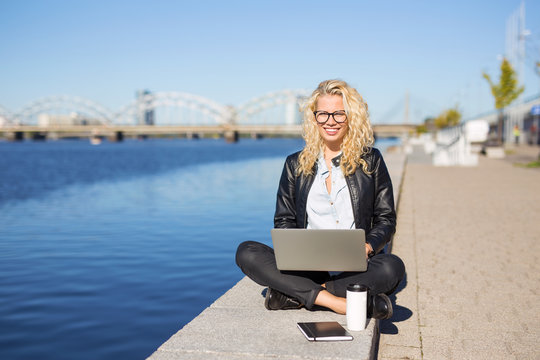 Hipster woman sitting outside and working on laptop