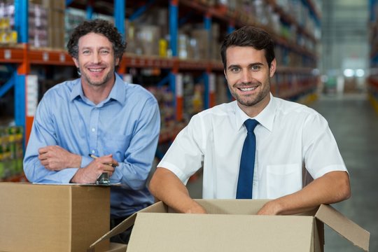 Portrait of two warehouse workers standing together with boxes 
