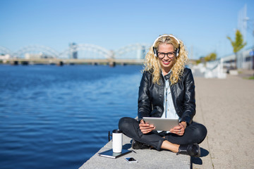 Woman listening music on headphones with tablet in her hands